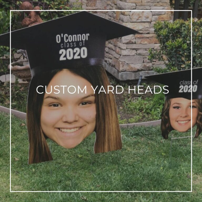 custom photo yard heads of a woman's wearing a graduation cap arranged on a front lawn outside a house