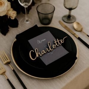 Gold laser-cut script name Charlotte on a menu card and black plate, unedited product photo