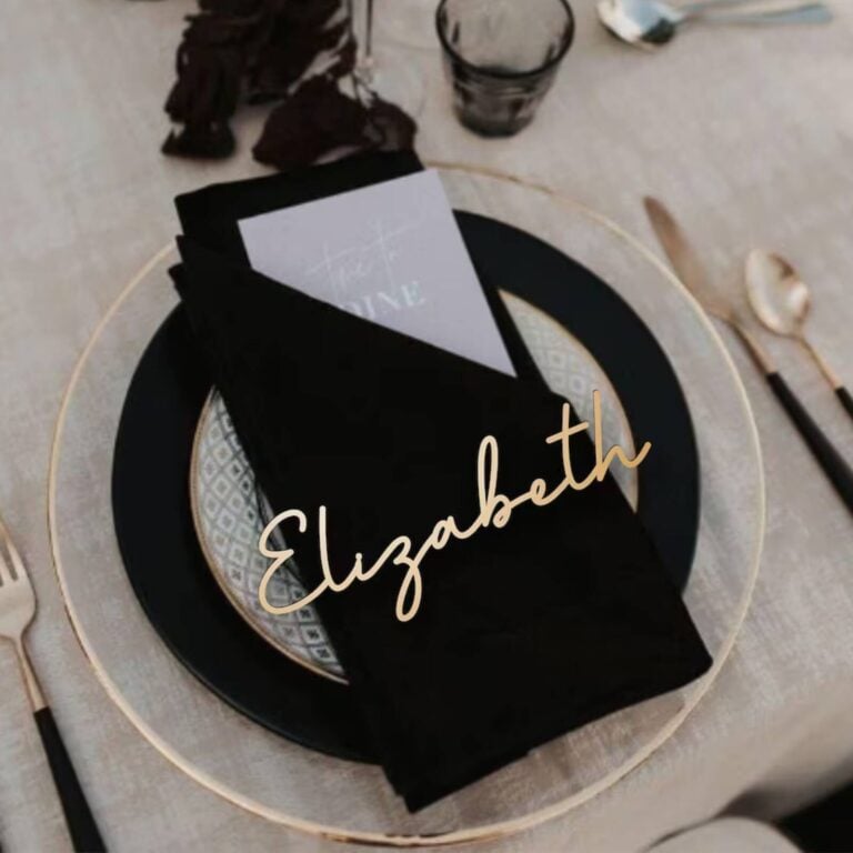 Gold script name Elizabeth on a black napkin over a black plate with a gold rim