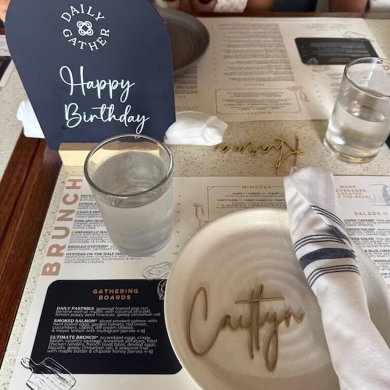 Gold script name Caitlyn on a white plate at a brunch table with a Happy Birthday sign