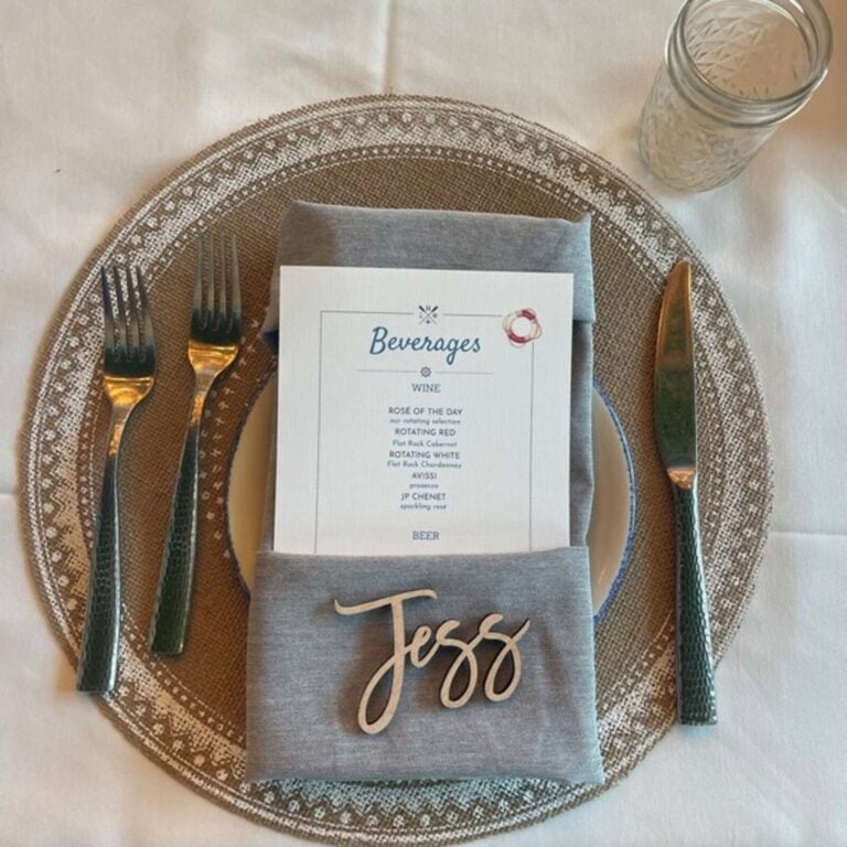 Light wood script name Jess on a grey napkin with a beverage menu on a woven charger