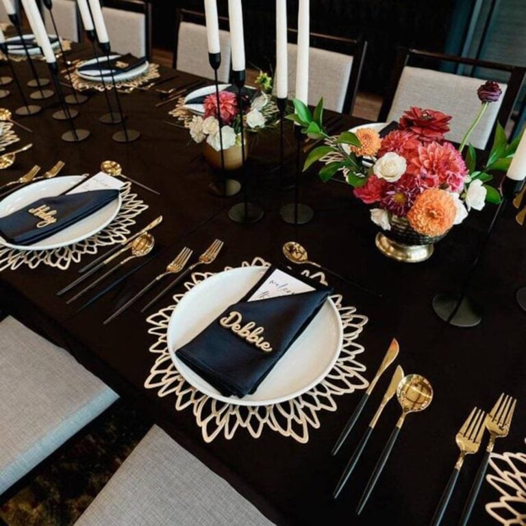 Gold script name Debbie on a black napkin at a black table with gold lace placemats