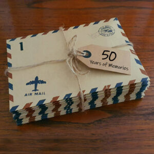 stack of 50 years of memories letters in airmail envelopes for a 50th birthday party