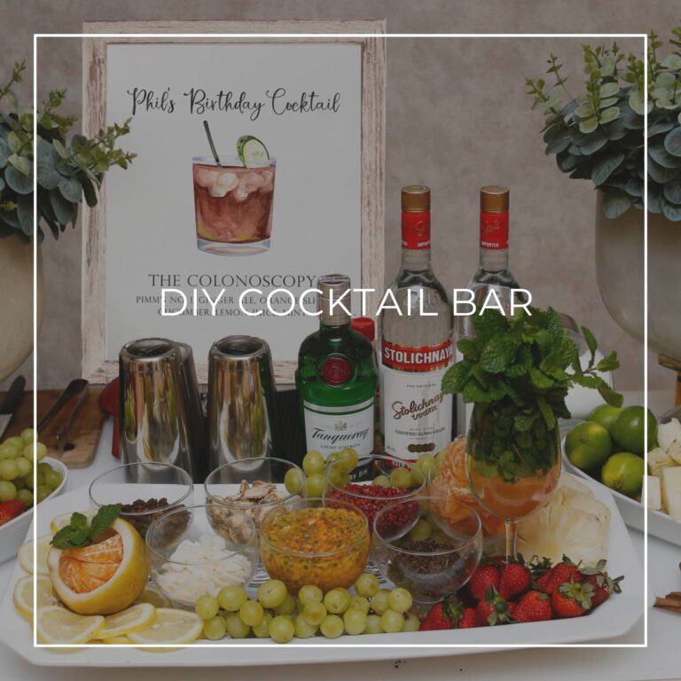 DIY cocktail bar with liquor, ingredients, and a cocktail recipe sign for party guests to make their own drink