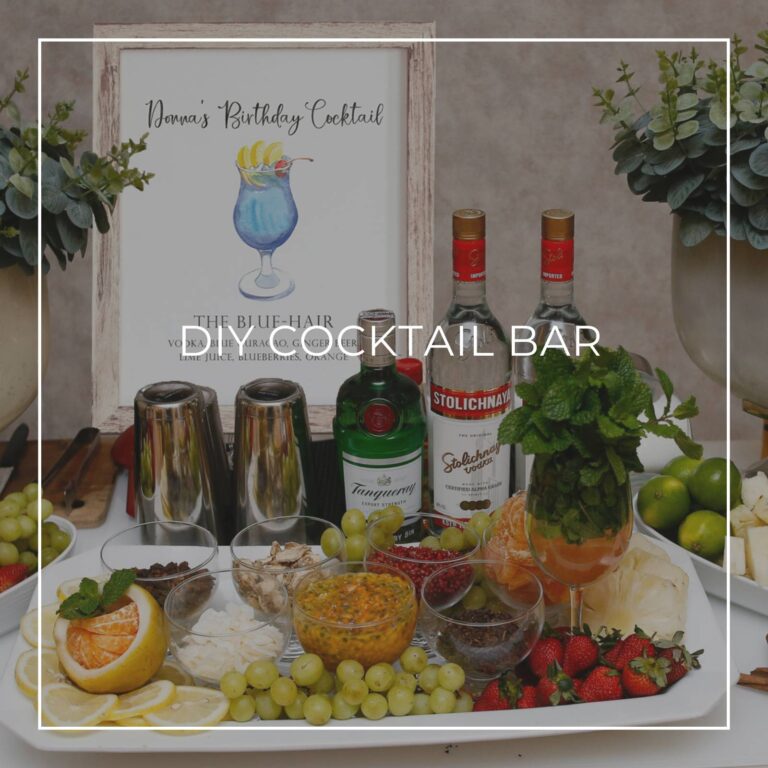 DIY cocktail bar with liquor, ingredients, and a cocktail recipe sign for party guests to make their own drink