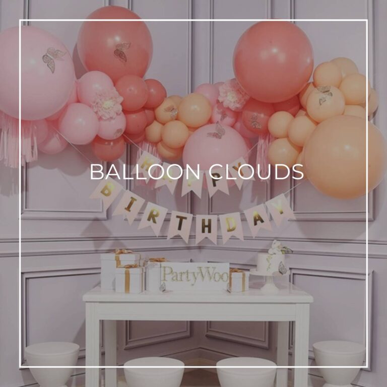 pink, red, and orange balloon 'cloud' garland and happy birthday banner hung above a party table