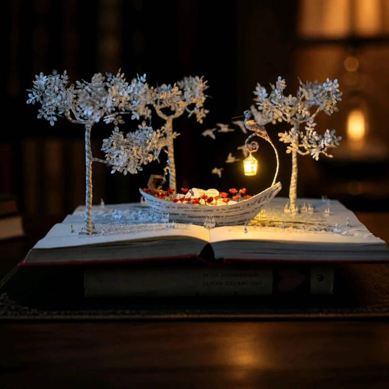 Glowing paper boat filled with red flowers and a lantern, surrounded by trees and birds, on an open book