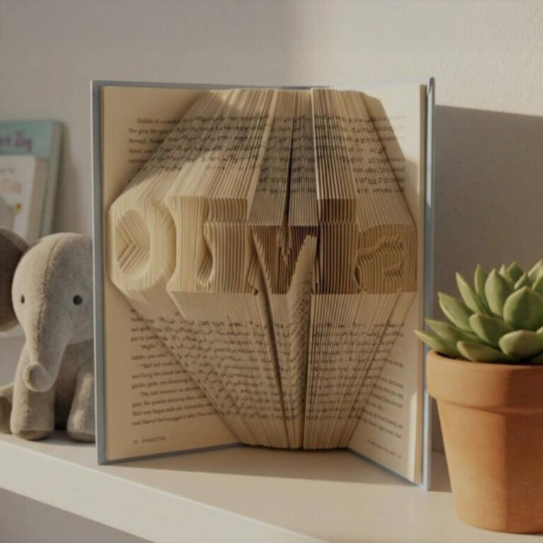 Book folding art personalized with the name “Olivia” displayed on a nursery shelf beside a plush elephant and succulent