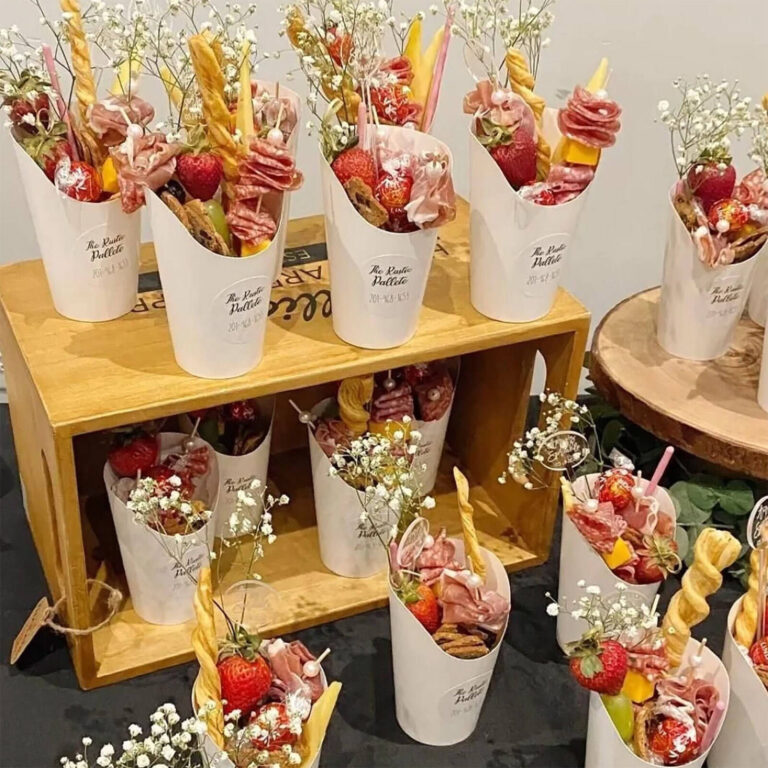Individual charcuterie cups with custom labels on a buffet table