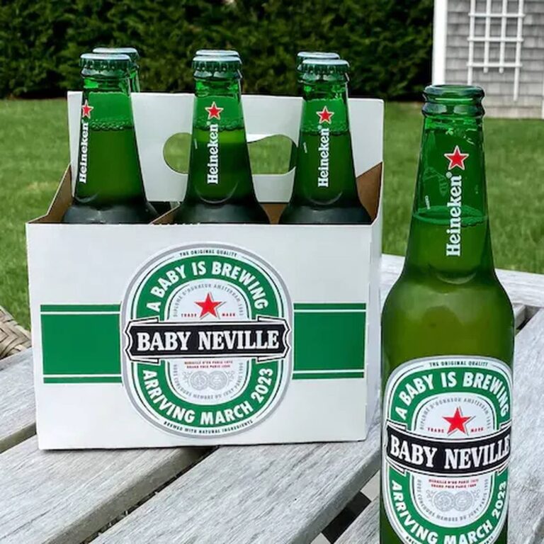 Six-pack of Heineken bottles with a custom "A Baby Is Brewing, Baby Neville, Arriving March 2023" baby shower label