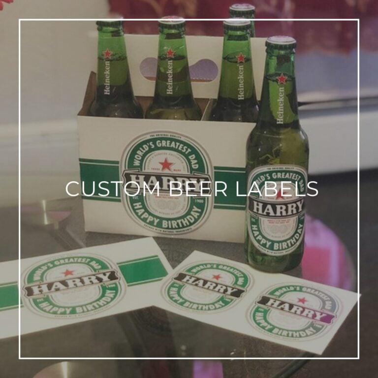 Six-pack of Heineken bottles with custom "World's Greatest Dad, Harry, Happy Birthday" labels next to printed label sheets, labeled "Custom Beer Labels"
