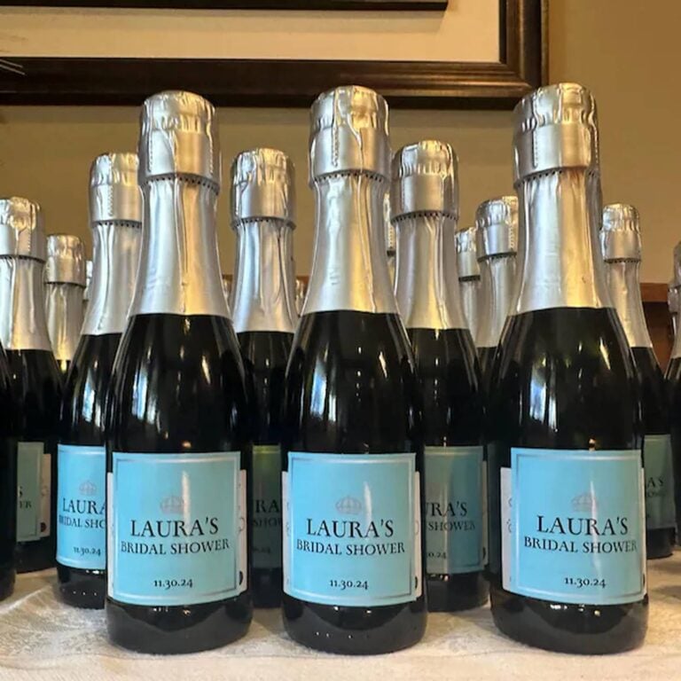 Rows of mini champagne bottles with light blue "Laura's Bridal Shower, 11.30.24" labels