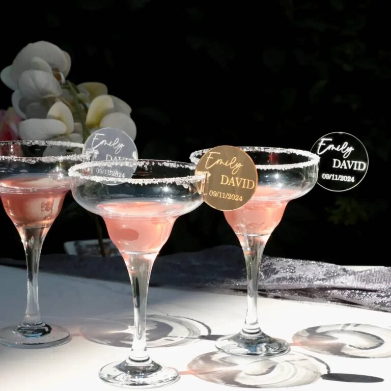 Three sugar-rimmed pink cocktails with silver, gold, and black round drink charms engraved “Emily DAVID 09/11/2024”