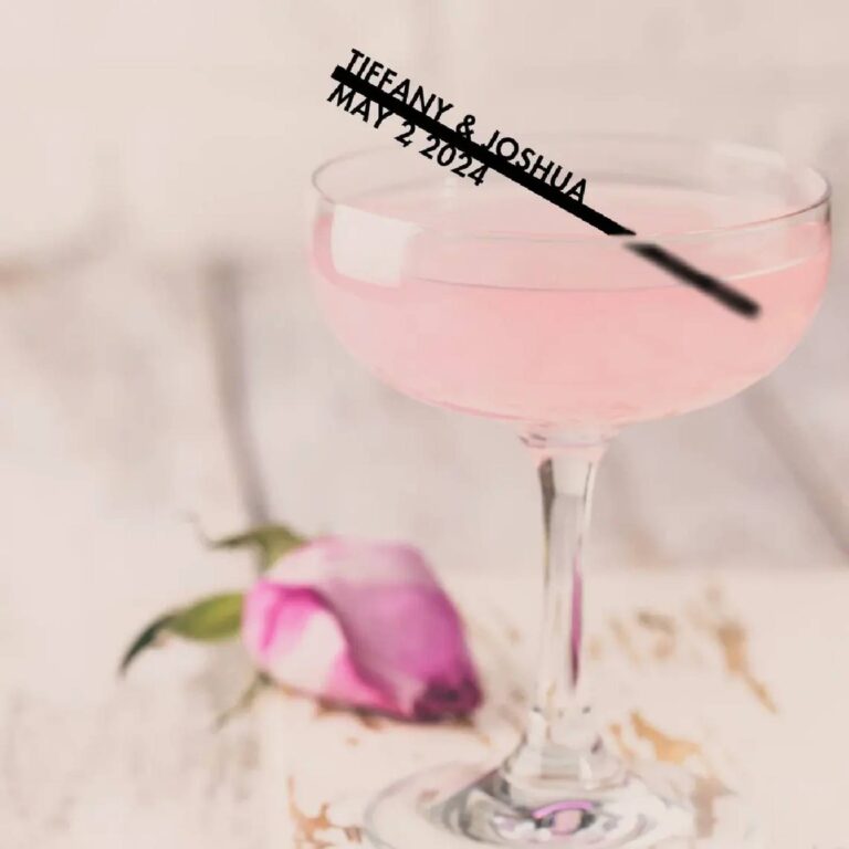 Pink cocktail in a coupe glass with a black acrylic stirrer reading “Tiffany & Joshua, May 2 2024”