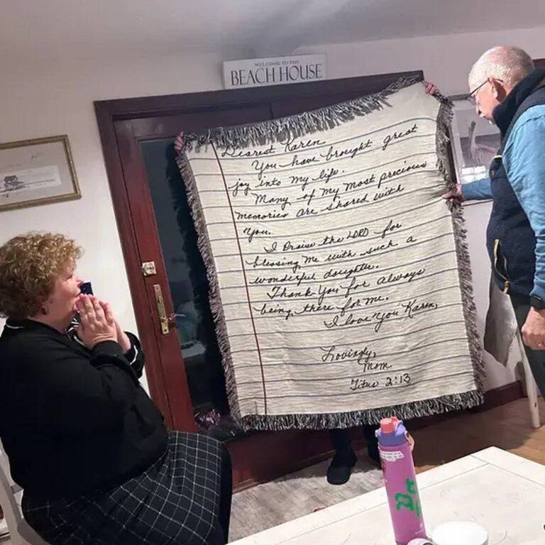 Blanket with a letter to ‘Dearest Karen’ signed ‘Lovingly, Mom’ with Titus 2:13, held up indoors