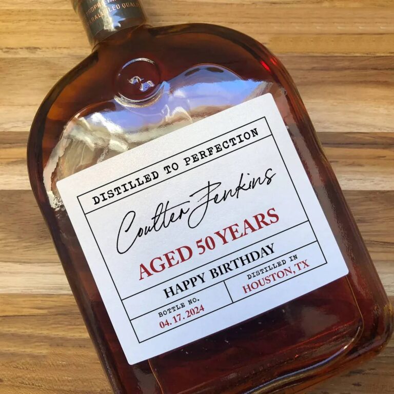 Bottle on a wood table with a "Distilled to Perfection, Coulter Jenkins, Aged 50 Years, Happy Birthday" label