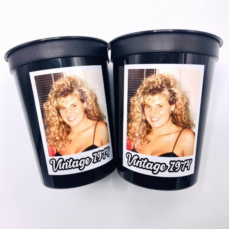 Two black stadium-style photo cups printed with a woman’s big curly-hair photo and “Vintage 1974”