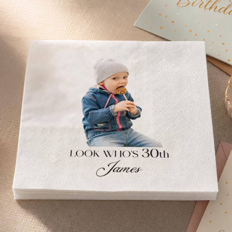 “Happy 80th Birthday, Ronald” napkin with a photo of Ronald in sunglasses and a pink crocheted hat