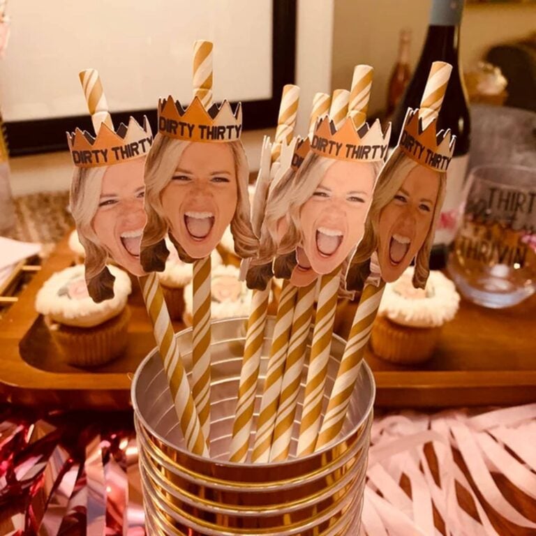 Gold and white striped photo straws topped with a laughing woman’s face wearing a “Dirty Thirty” paper crown, cupcakes in the background
