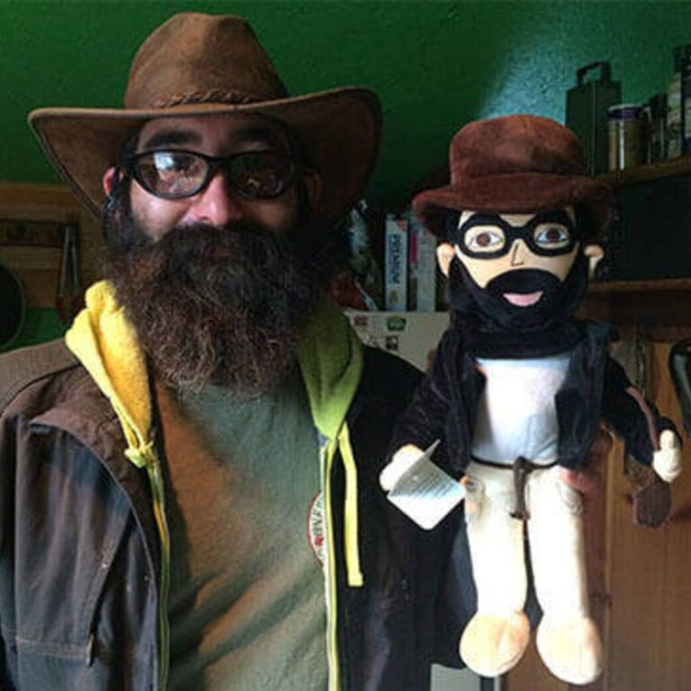 Bearded man in a cowboy hat next to his matching custom plush doll