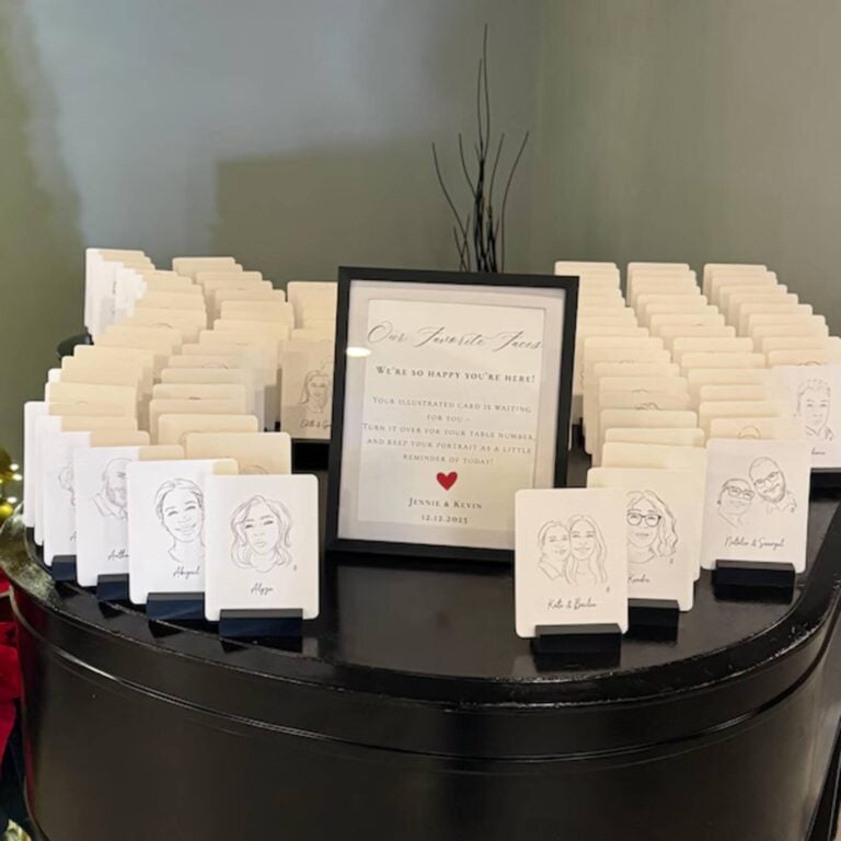 Line-drawing portrait place cards on black stands at a wedding, beside an Our Favorite Faces sign