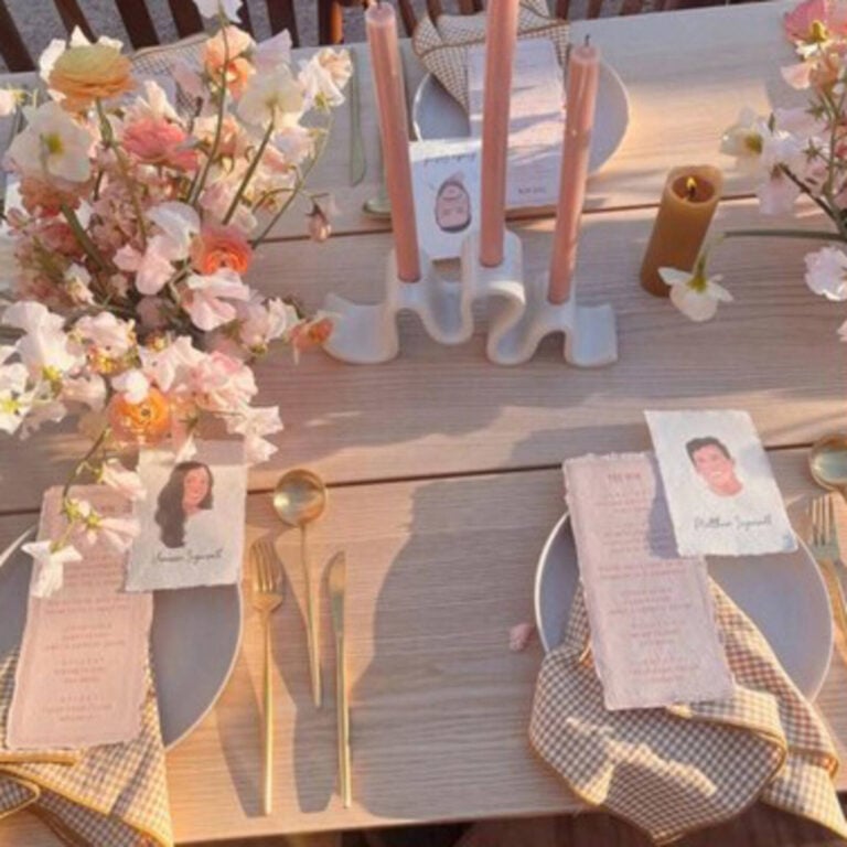 Portrait place cards on a pastel wedding table with pink candles, flowers and gold cutlery