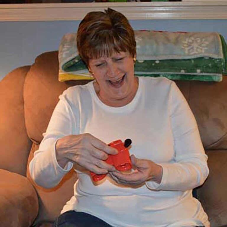 Woman laughing as she holds a red reel viewer, not yet looking through it, at Christmas