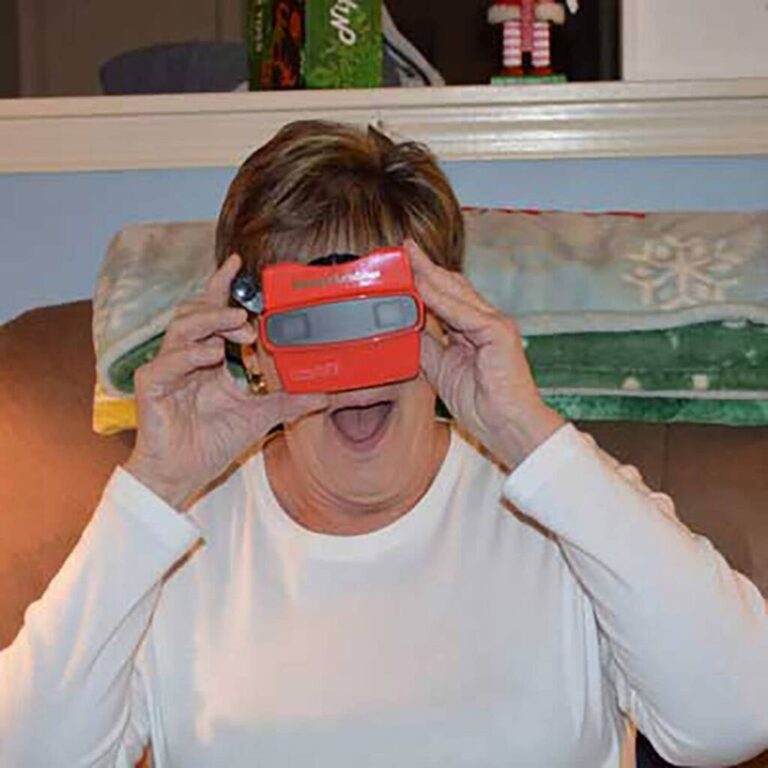 Woman gasping with surprise while looking through a red reel viewer at Christmas