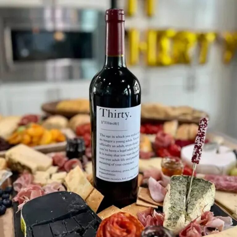 Wine bottle with a “Thirty.” definition-style label at a 30th birthday charcuterie spread