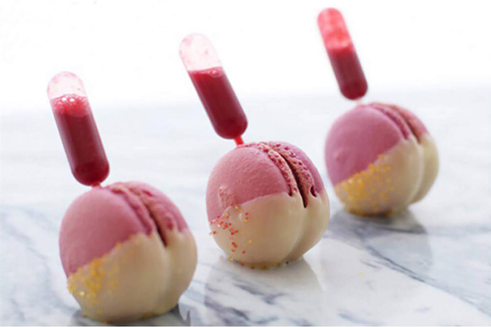 macarons with sauce in pipettes laid out in rows