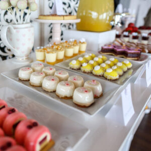 desserts laid out in rows on square and rectangular plates on a party dessert table