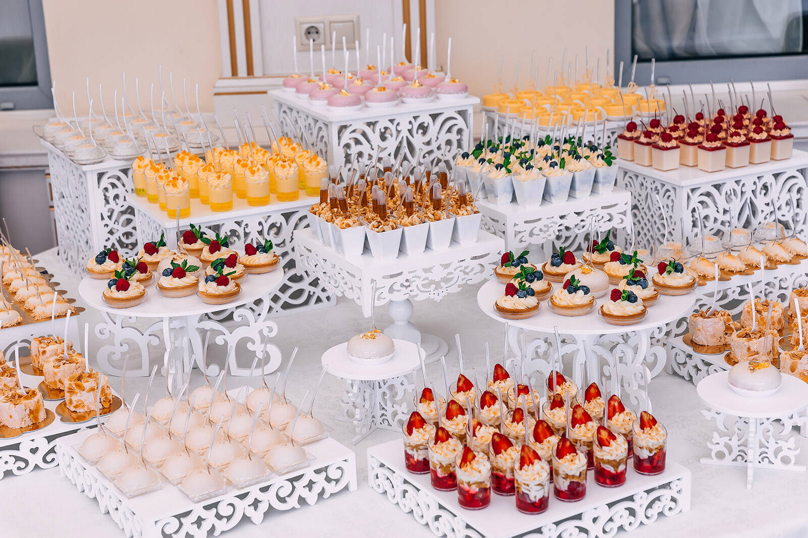 a variety of different mini desserts on cake stands on a party dessert table