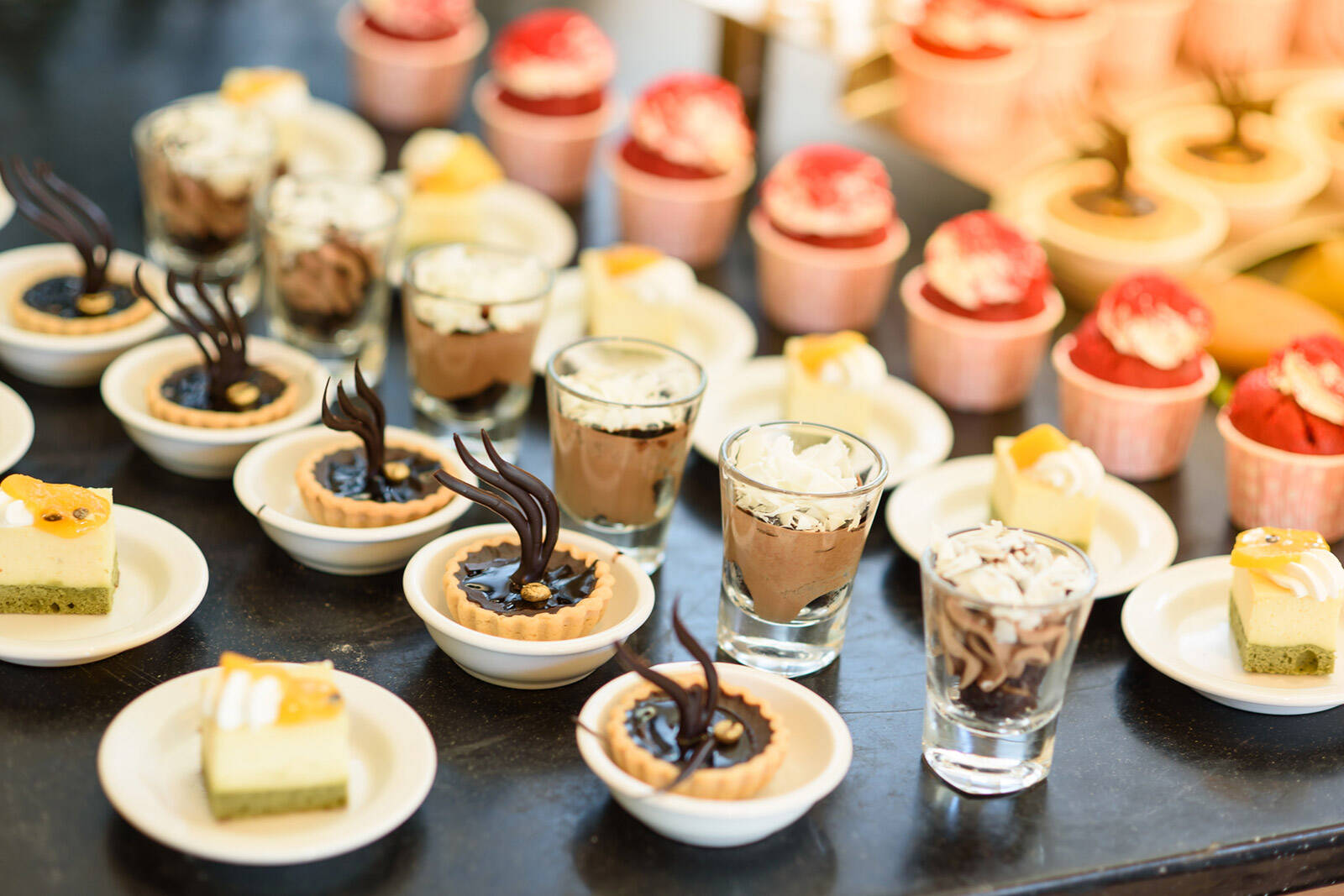 a variety of different mini desserts arranged in rows on a party dessert table