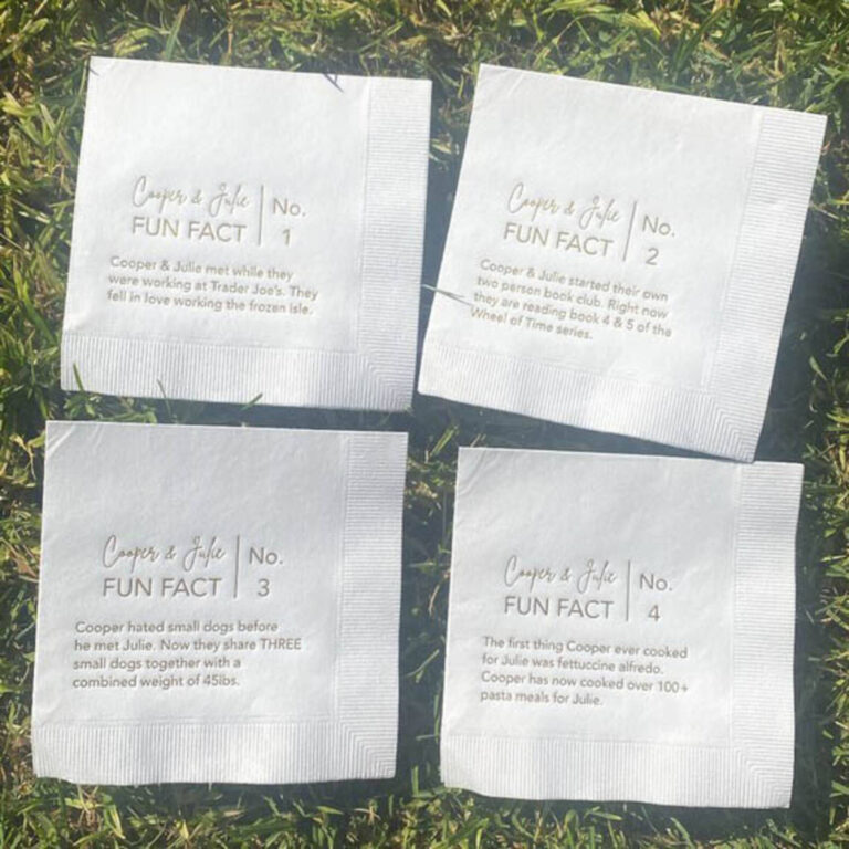 “Cooper & Julie Fun Fact” napkins No. 1-4 on grass, each printed with a different fact about the couple