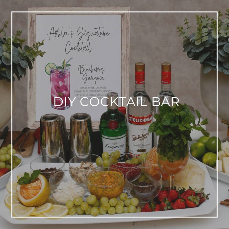 DIY cocktail bar with liquor, ingredients, and a cocktail recipe sign for party guests to make their own drink