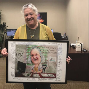 woman holding a retirement party guest book alternative signing poster with an illustrated caricature of herself