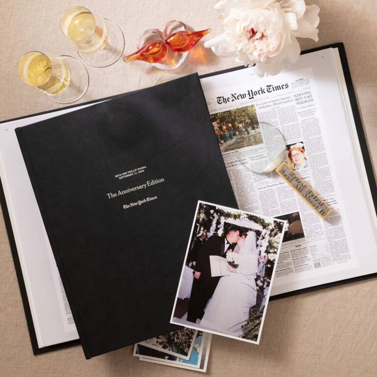 Personalized New York Times Anniversary Edition book cover for a couple, shown with champagne glasses and a wedding photo