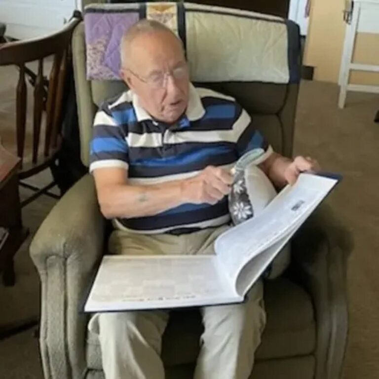 Elderly man reading his personalized Historic Headlines Birthday Book with a magnifying glass