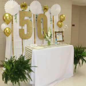 large flat cardboard number 50 painted gold and used as 50th birthday dessert table decorations