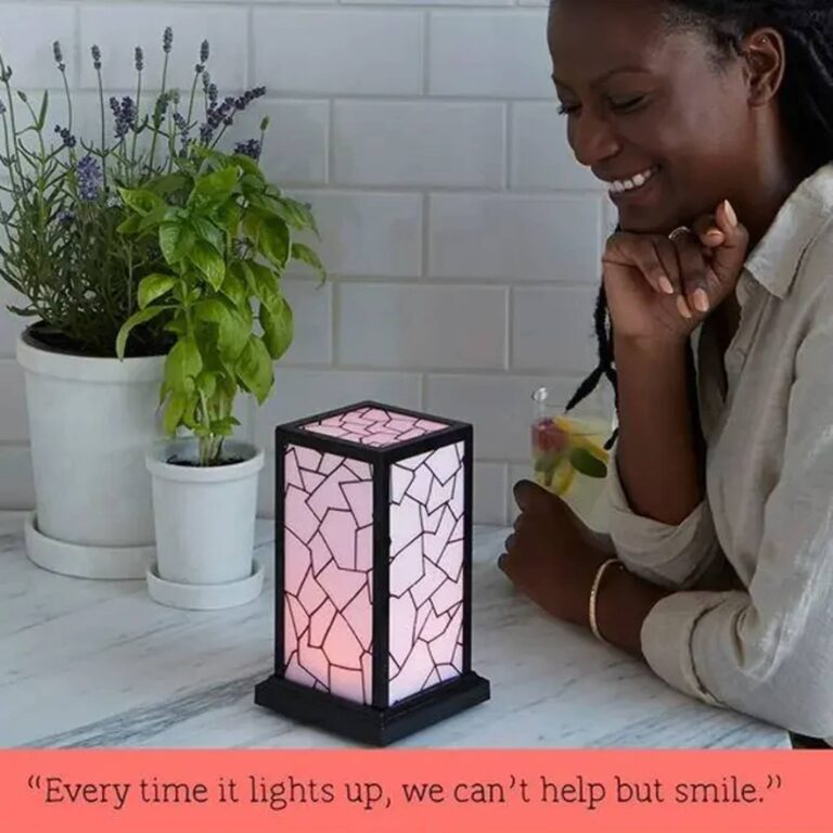 Pink-lit mosaic touch lamp on a kitchen counter beside potted herbs