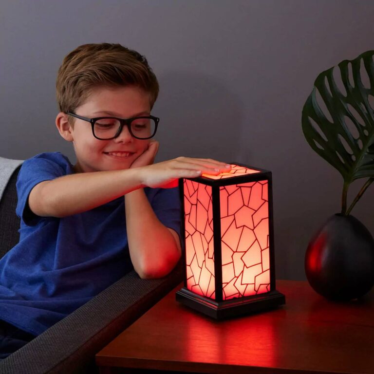 Boy touching a red-glowing mosaic lamp on a living room side table