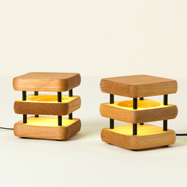 Two wooden friendship lamps lighting up together to demonstrate their synced touch-activated glow
