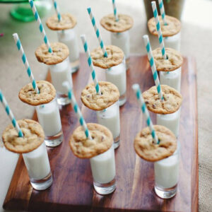 milk served in individual milk bottles with a cookie and straw on a party dessert table