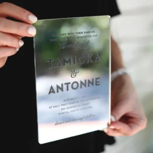 Mirrored acrylic wedding invitation for Tamicka and Antonne held in a woman's hands
