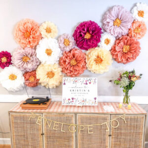 colorful paper flower decorations hanging above a party welcome table