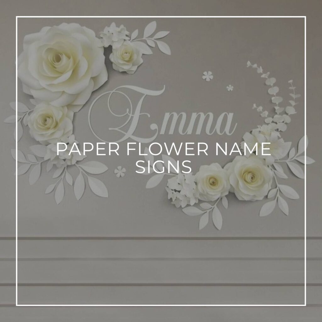 white paper flower and name sign spelling EMMA attached to a gray colored wall