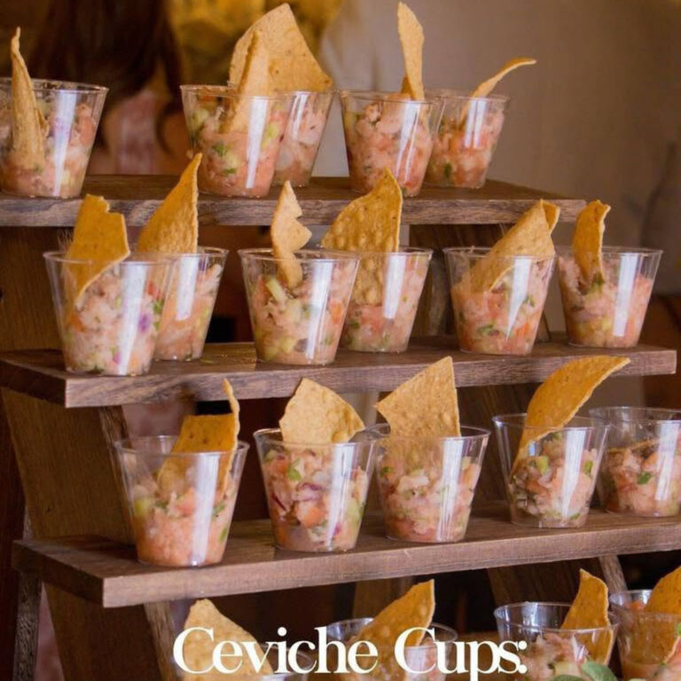 Ceviche appetizer cups displayed on a tiered wood stand with tortilla chip garnish