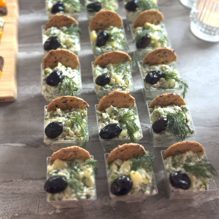 Egg salad appetizer cups topped with a black olive, dill, and a cracker
