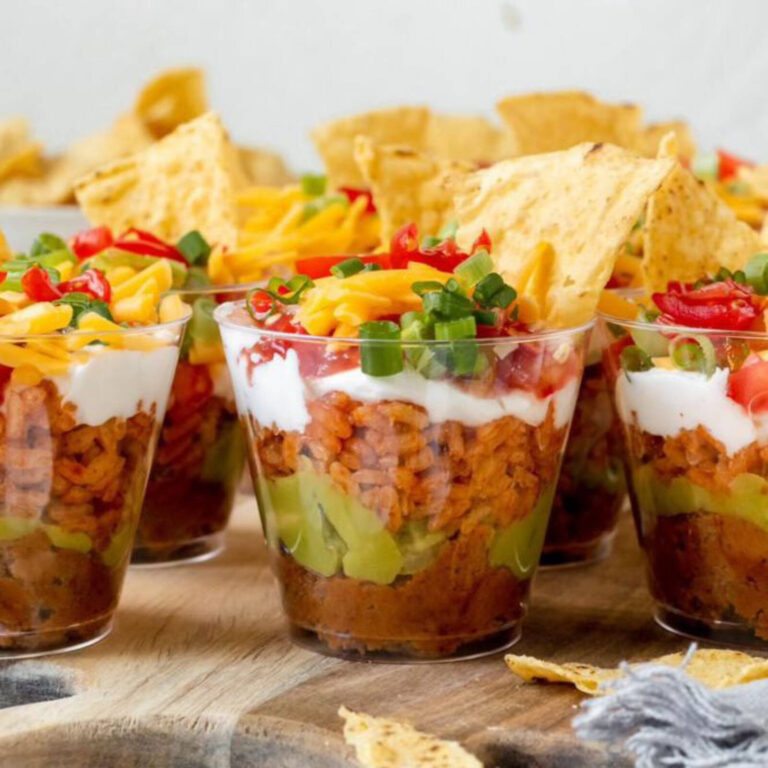 Seven-layer taco dip appetizer cups with beans, rice, guacamole, sour cream, and cheese