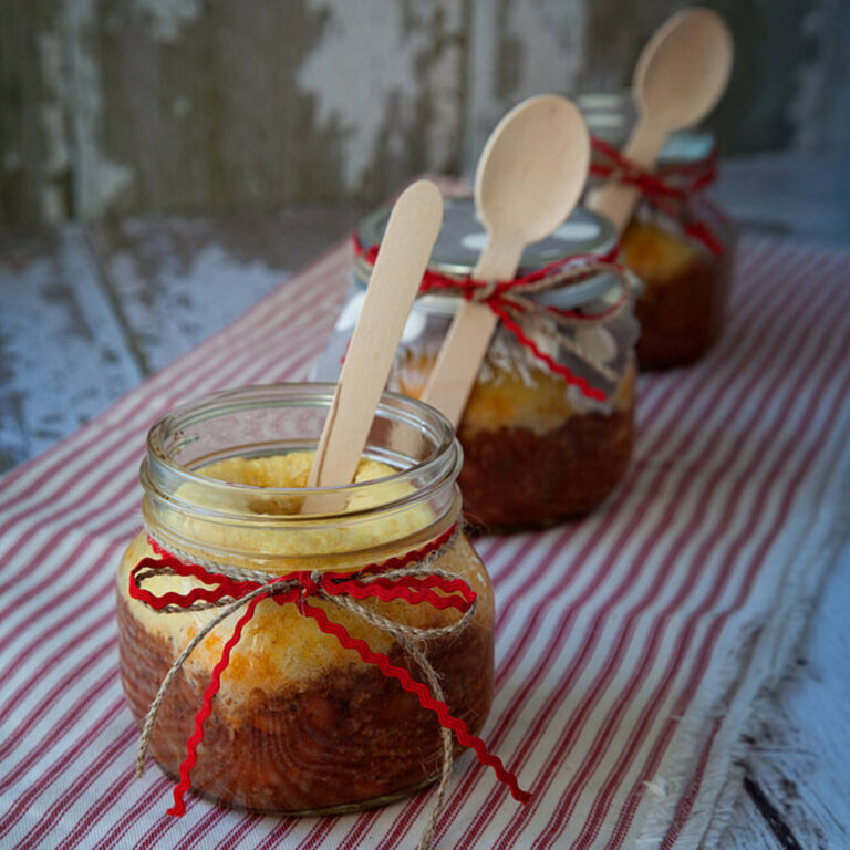 Mini dessert mason jars with cornbread cake, wooden spoons, and red ribbon ties on a rustic table